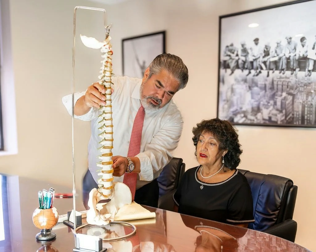César Valdebenito explica una lesión de columna con un modelo anatómico, en la oficina de Hempstead.